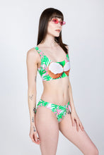 Load image into Gallery viewer, A woman in The Piña Colada | Tropical Coconuts Bikini Bottoms, sipping a Miami Vice cocktail, feeling good and giggly.
